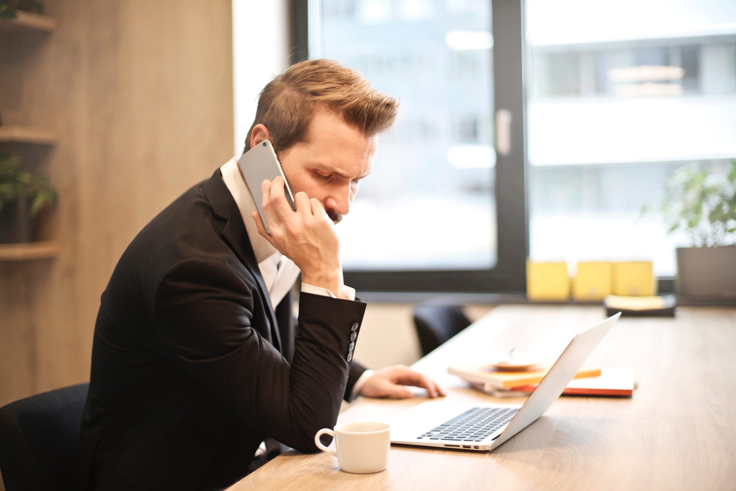 man-having-a-phone-call-in-front-of-a-laptop-859264